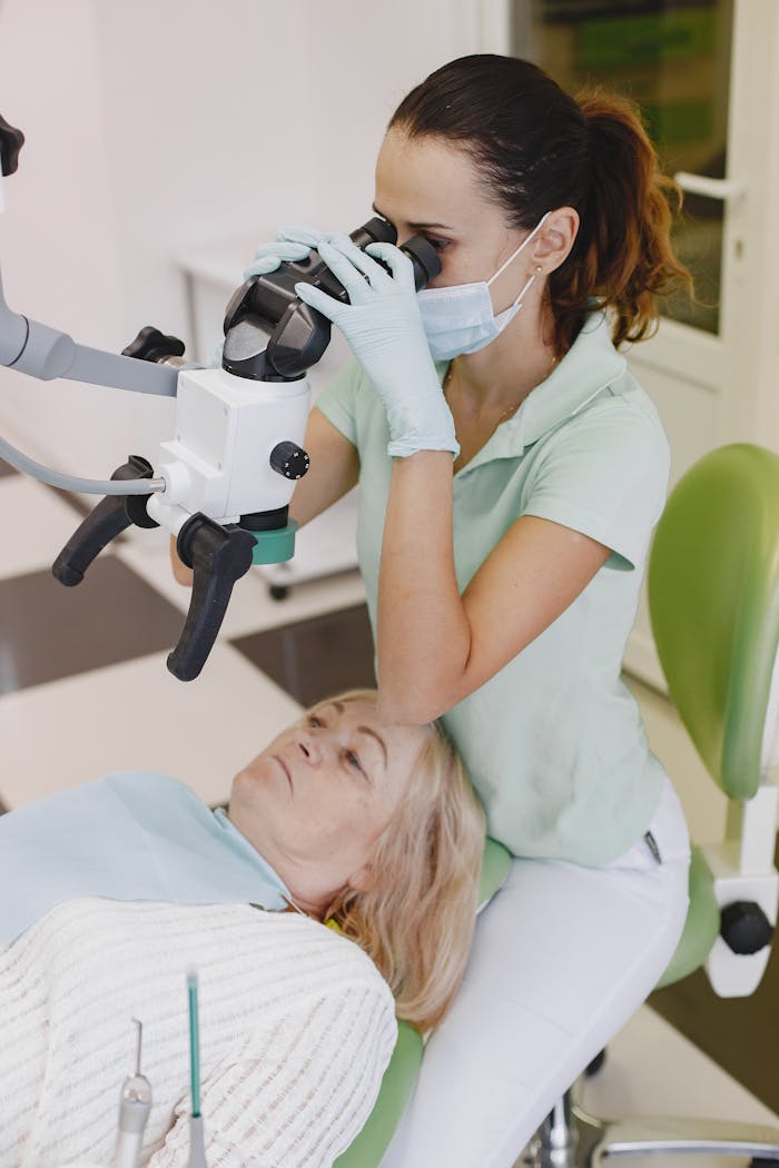 A female dentist uses a microscope for a detailed examination of an elderly woman's teeth in a dental clinic.